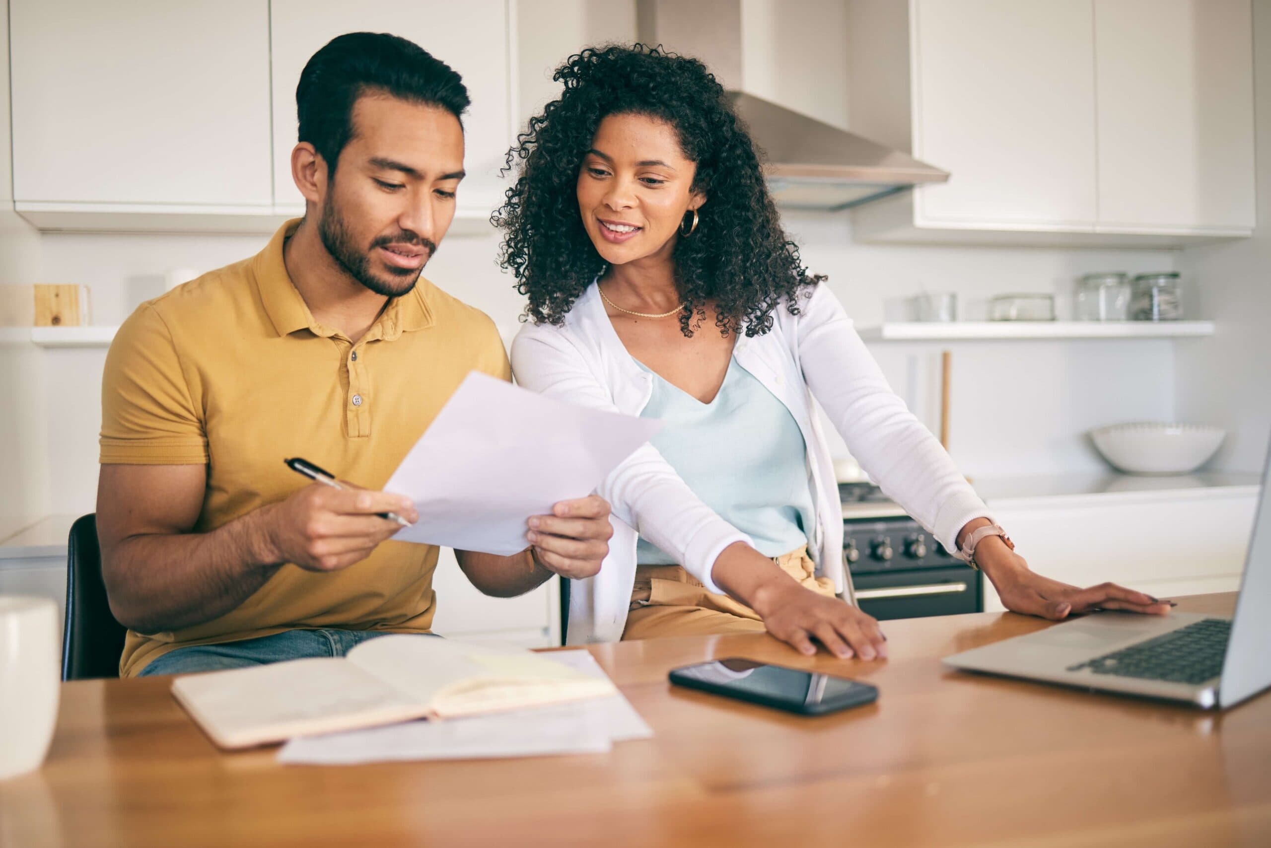 An engaged couple at their kitchen table, reading through their prenup together